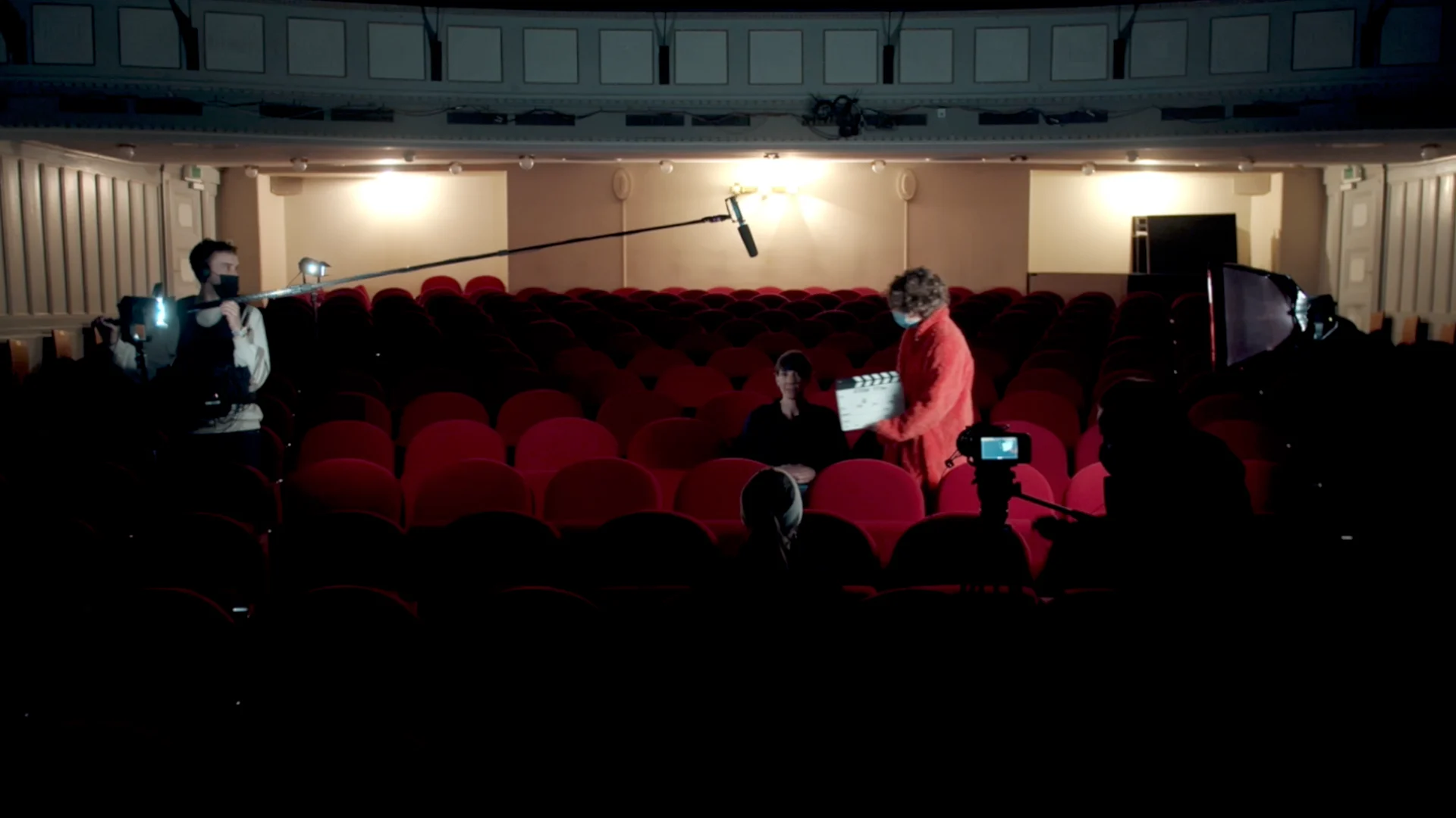 Cornland Studio - Backstage vidéo d'une salle de cinéma, une femme est assise dans des sièges rouge