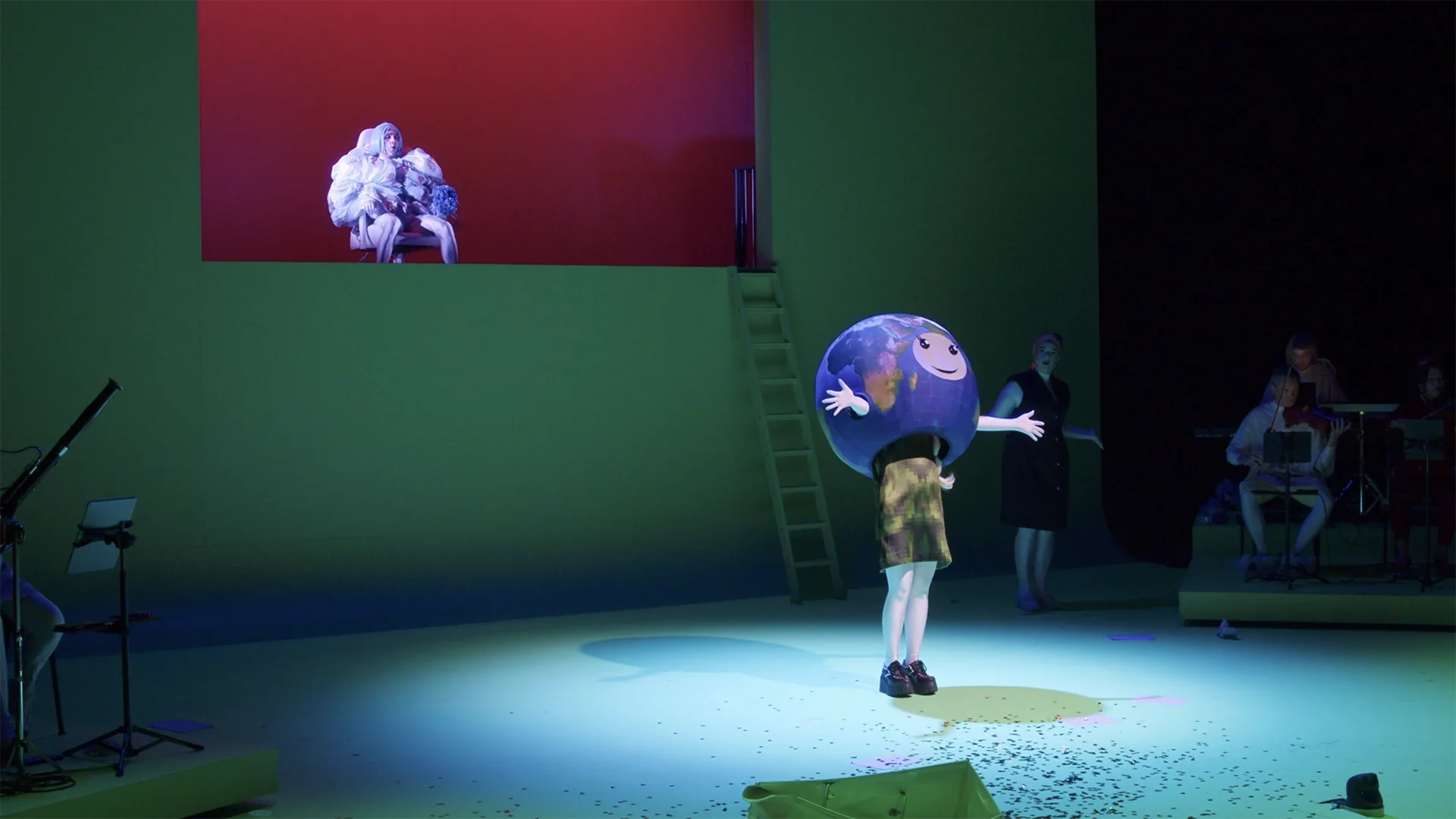 Cornland Studio - Vue d'ensemble d'une scène de théâtre, une femme est déguisée en planète terre au premier plan